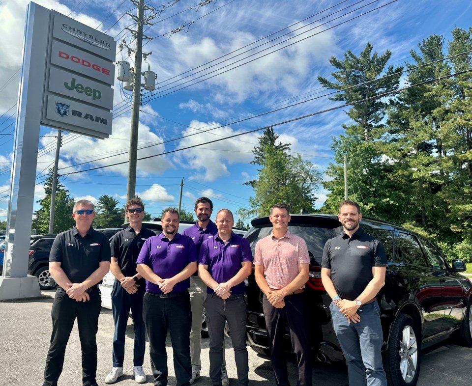 David Clayton, third from left, with six members of the Midland Chrysler team in front of the dealership sign