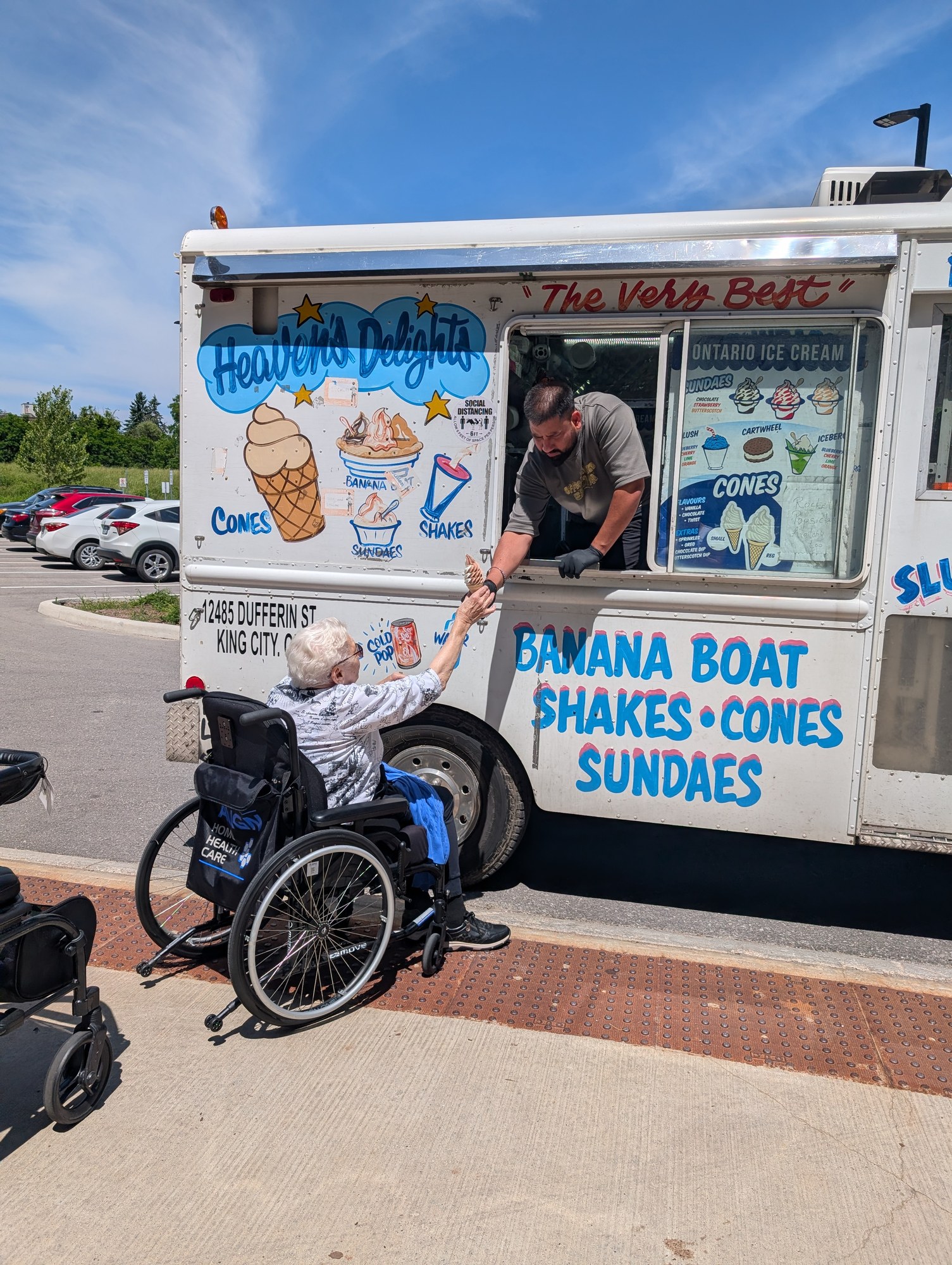 A resident in a wheelchair receiving ice cream from a truck