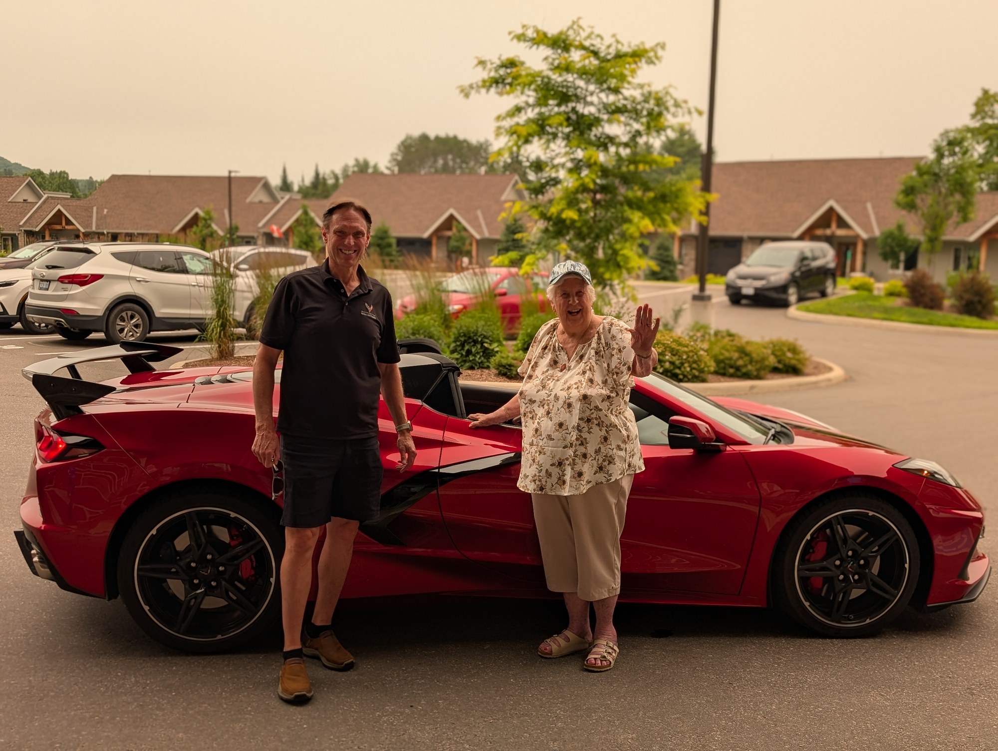 A resident and staff member standing with a red sports car