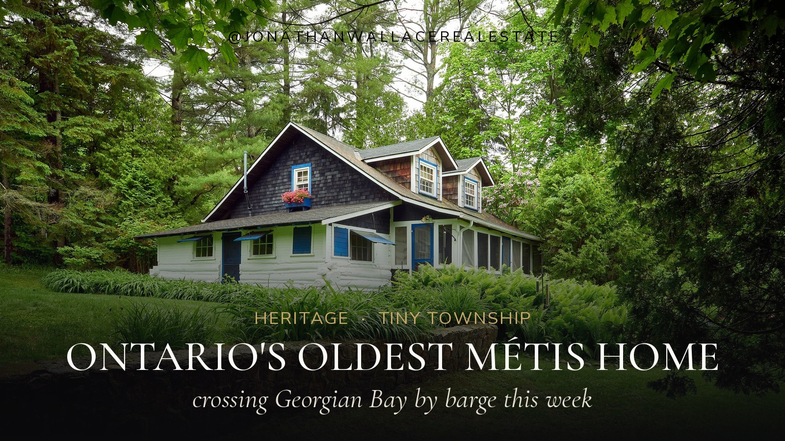 A white squared-log house with a dark shingled upper storey and blue trim among tall trees, titled Ontario's oldest Métis home, crossing Georgian Bay by barge this week