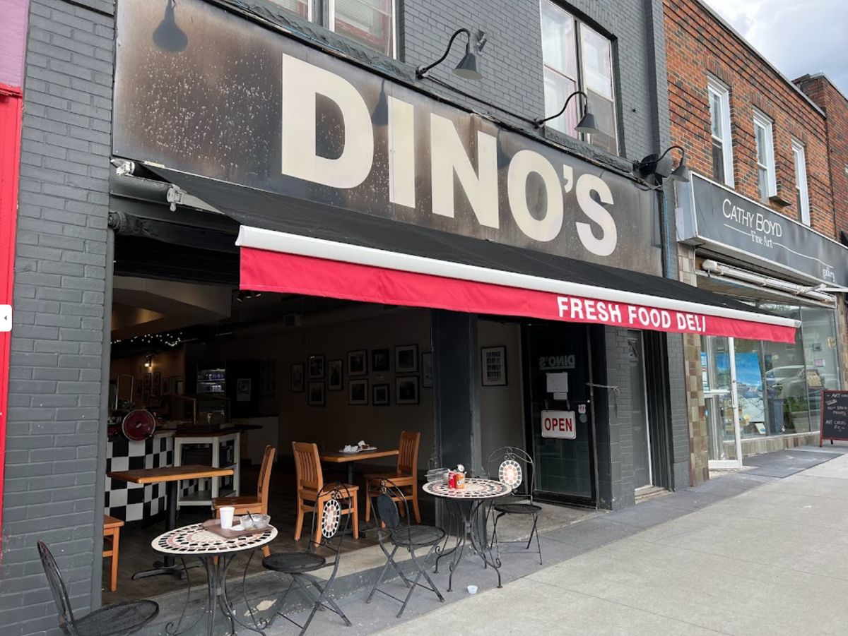 The front of Dino's Fresh Food Deli on King Street in Midland, with its red Fresh Food Deli awning and bistro tables on the sidewalk