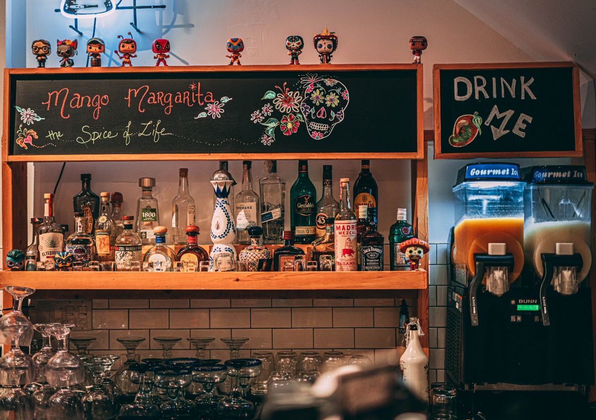 The bar at Zanca, with a Mango Margarita chalkboard, shelves of tequila and two slush machines