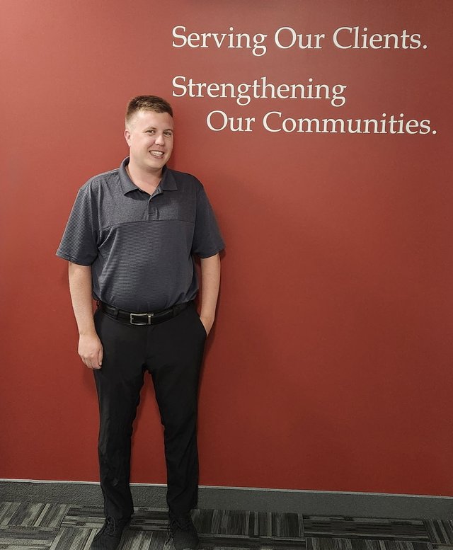 Ben Poole standing in front of the HGR Graham Partners wall that reads Serving Our Clients, Strengthening Our Communities